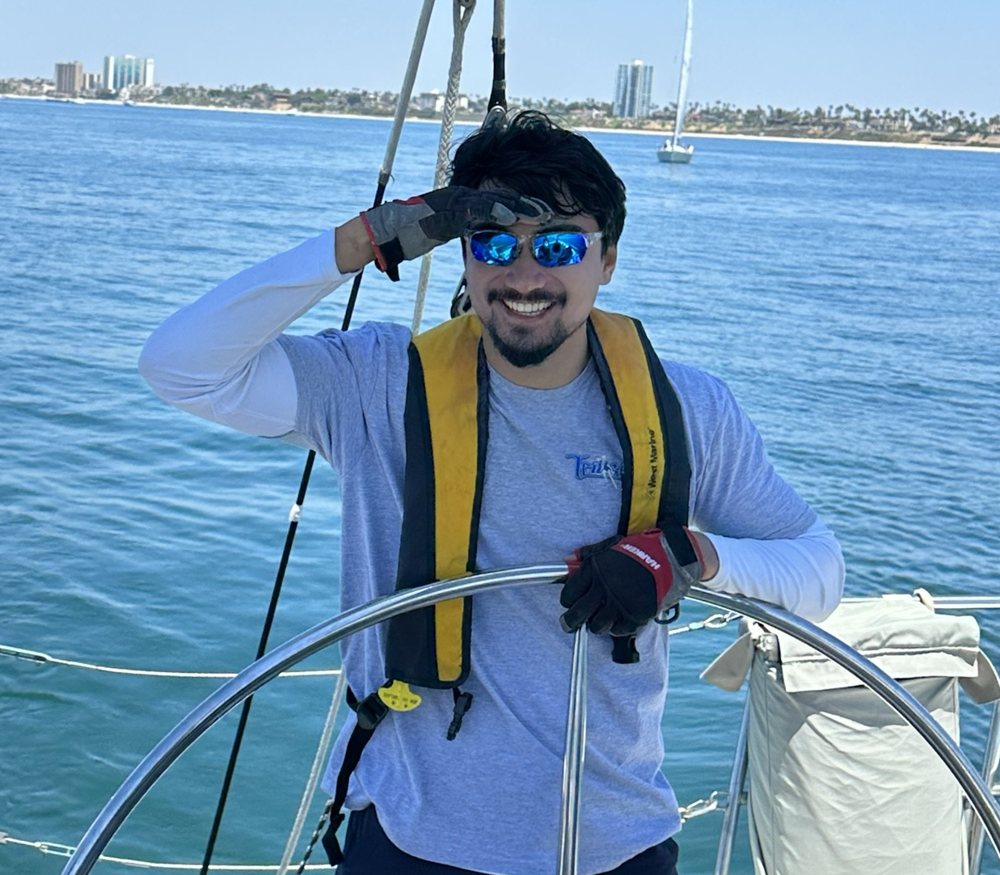 Onur Can smiling at the wheel of a sailboat